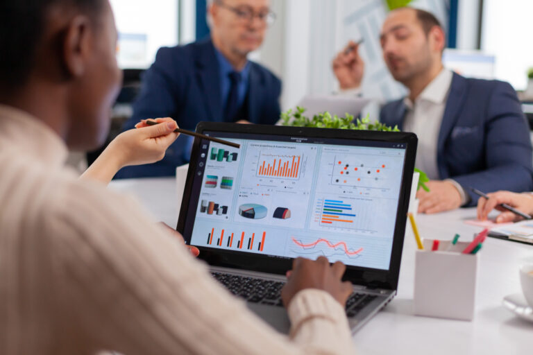 a woman in a board meeting using a laptop with tables and graphs