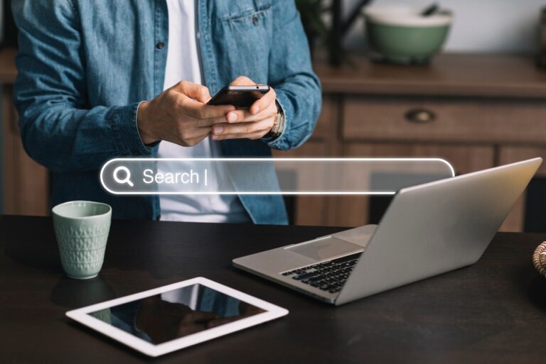 a man using phone laptop and tablet on table doing keyword research